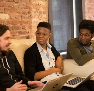 A Tumblr engineer and two Black folks sitting by a table
talking about code.